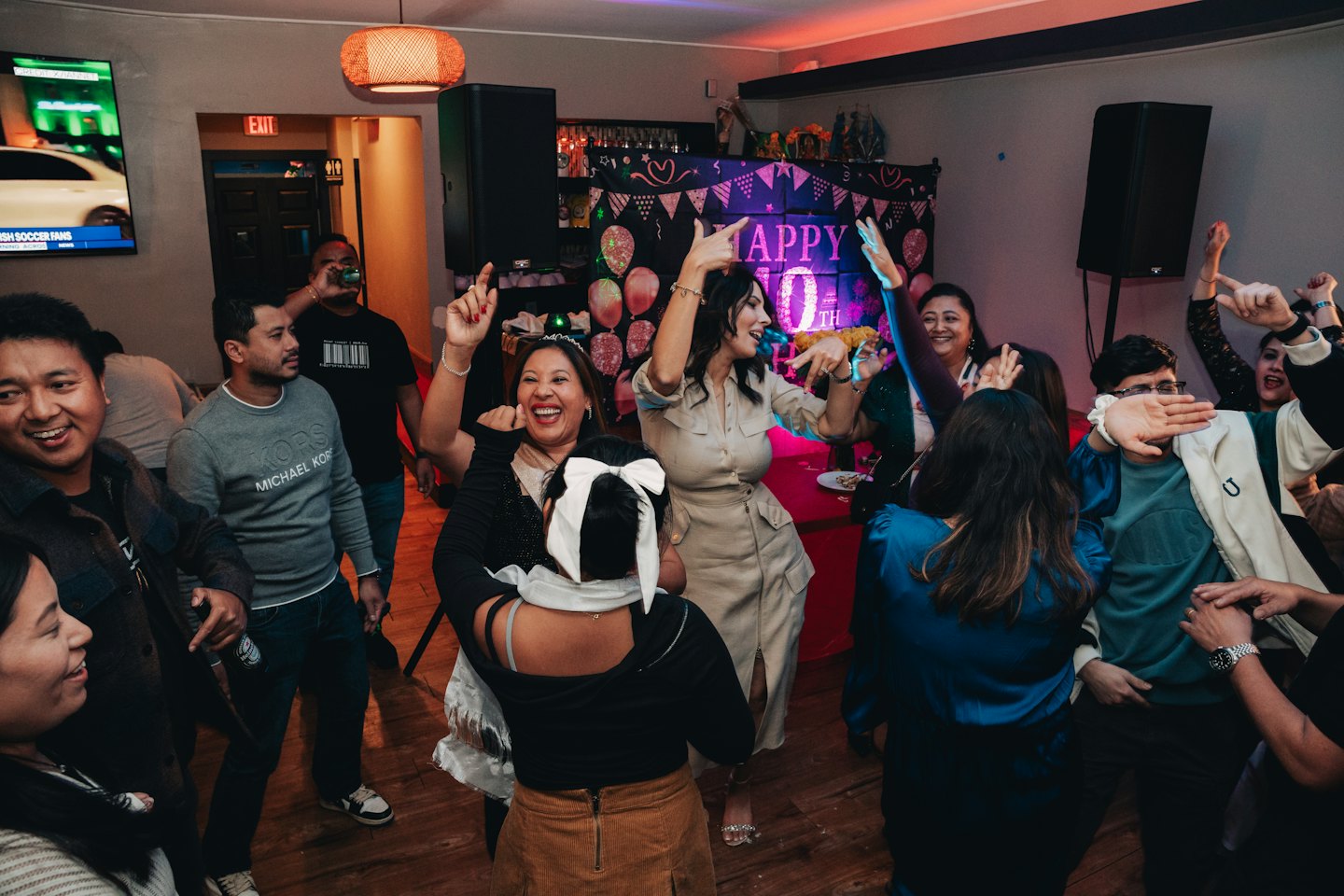 Un grupo diverso de adultos celebrando y bailando en un evento interior.
