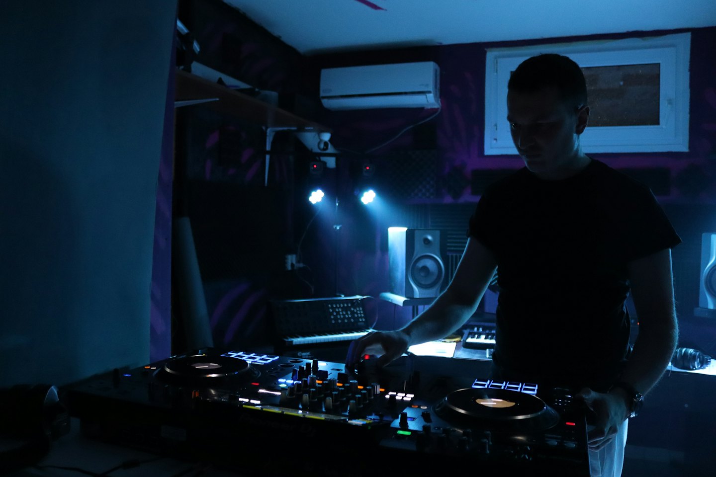 Joven mezclando música en un controlador de DJ en un club.