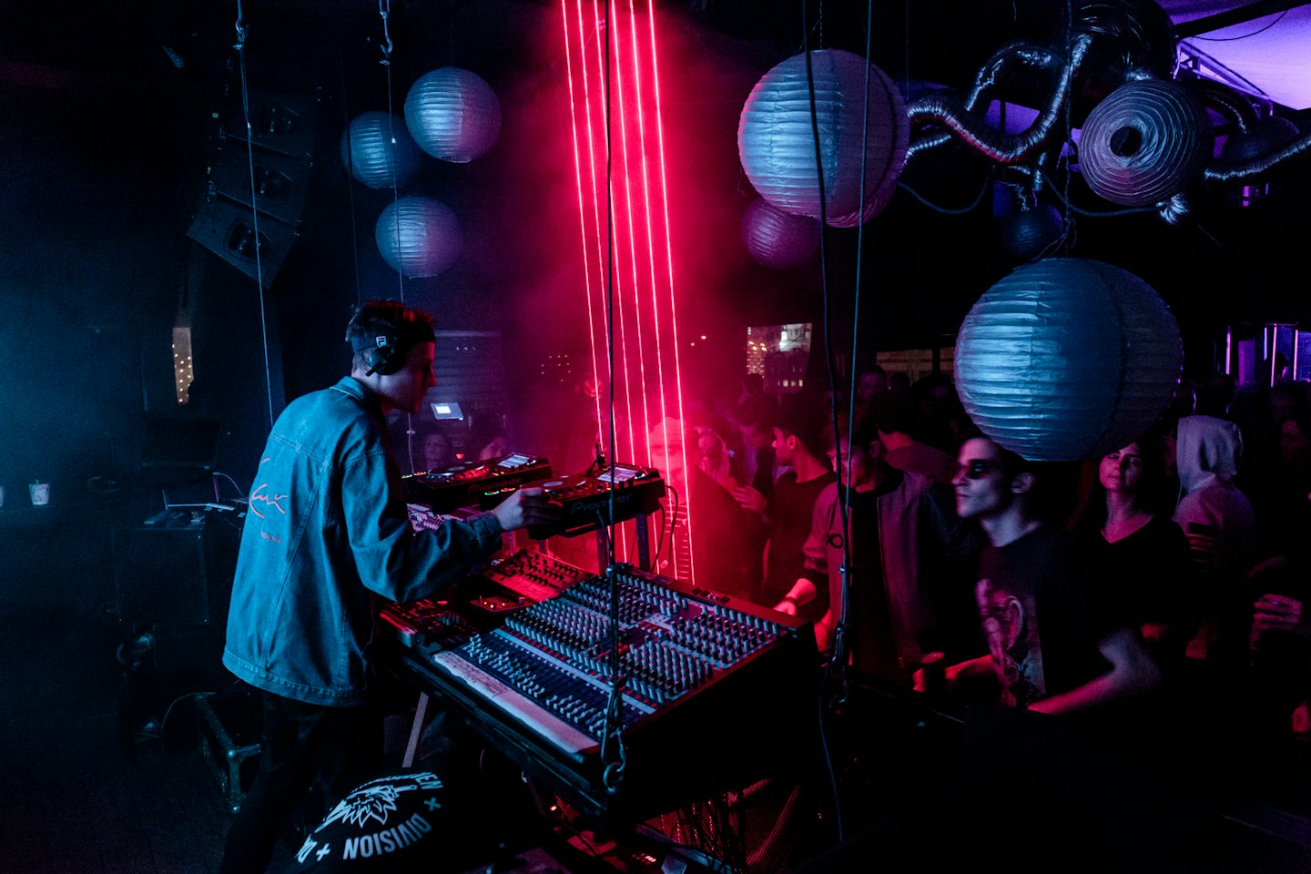 DJ mezclando música en una discoteca vibrante con luces de neón rojas.