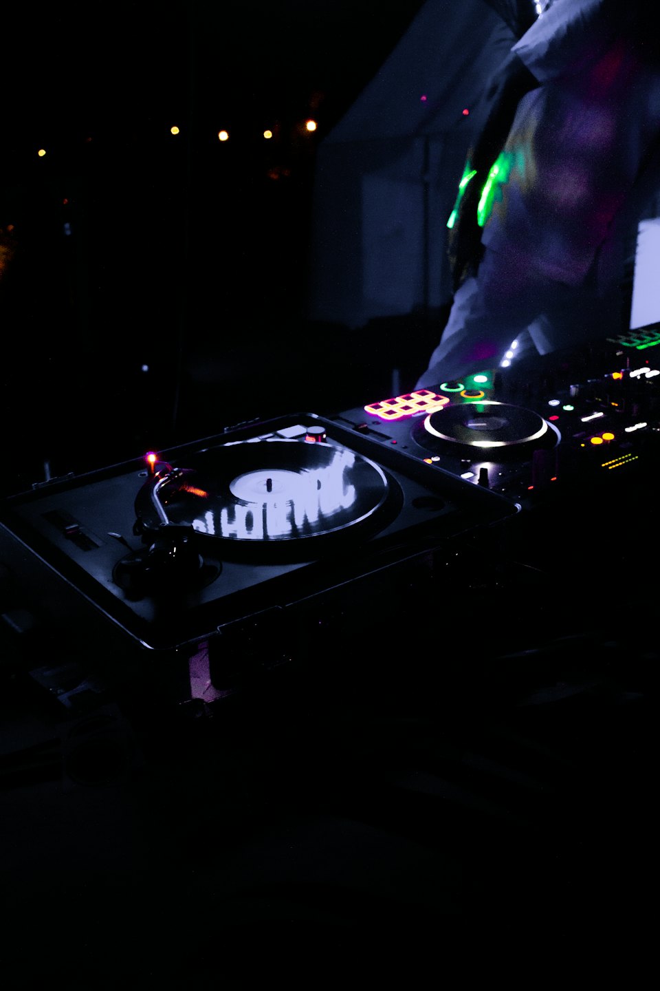DJ mezclando música en tornamesas con luces de colores.